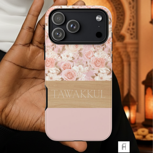Person holding a phone case with floral design and 'TAWAKKUL' branding, set against a warm-toned background.